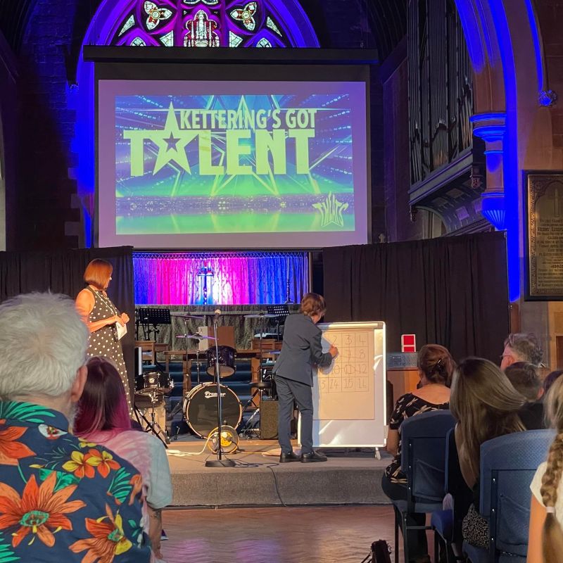 A young performer demonstrating a trick from Mind the Maths Magic on stage