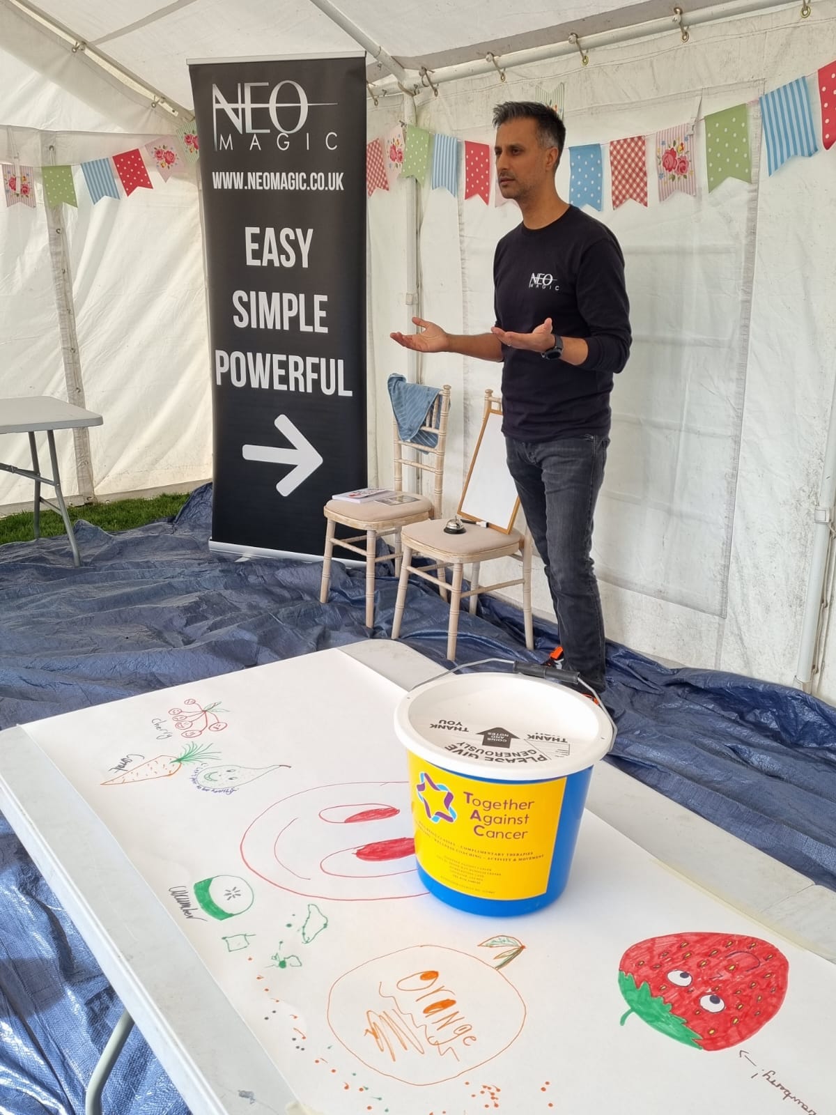 Vinny demonstrating magic at an event with a Together Against Cancer collection bucket